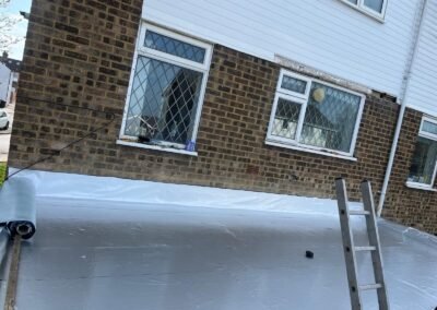 Single-ply membrane being laid on an extension flat roof